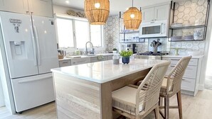 Una cucina moderna con isola centrale, mobili bianchi e forno a microonde.