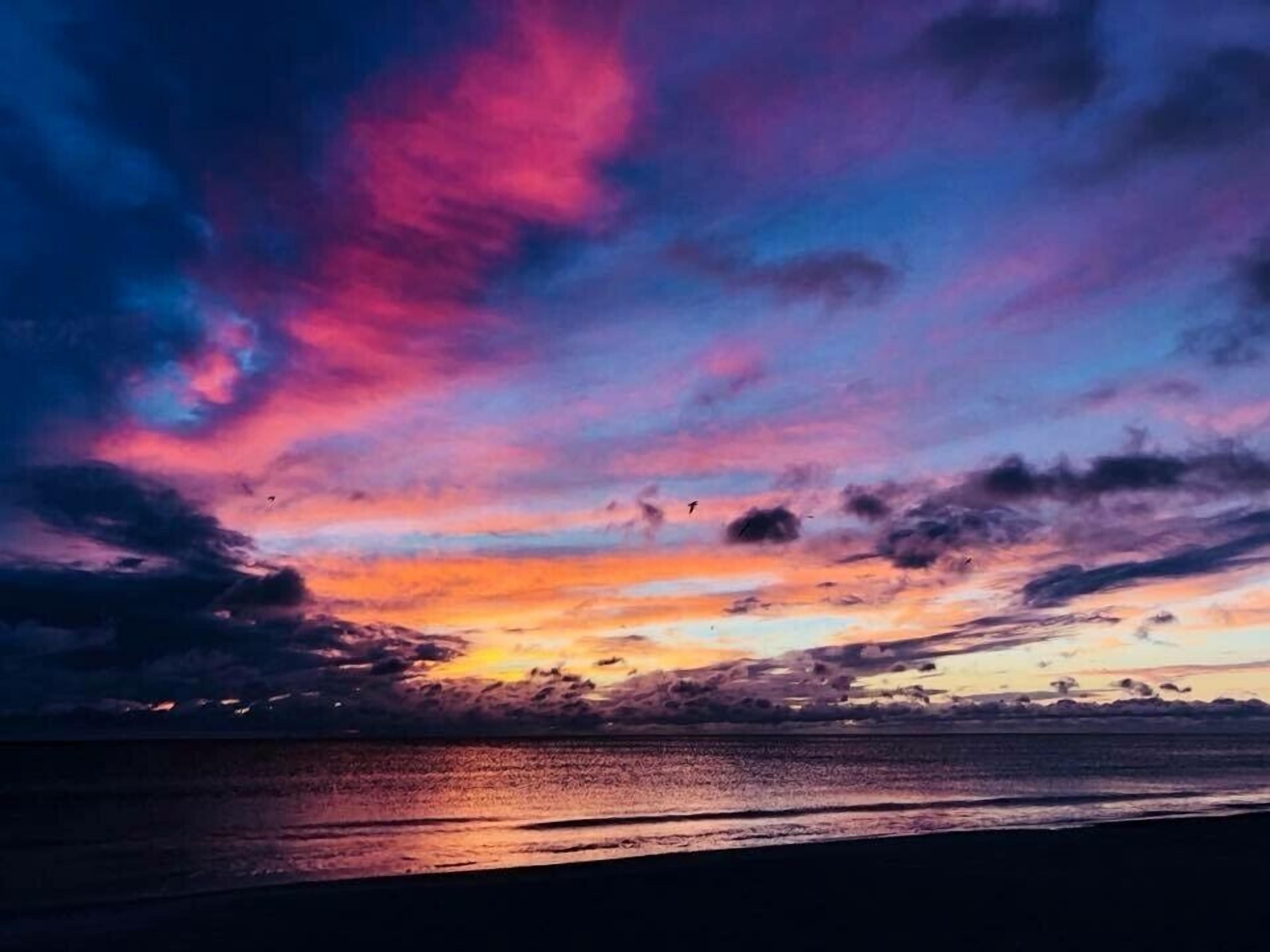 Tramonto su uno specchio d'acqua con cielo sereno e nuvole.