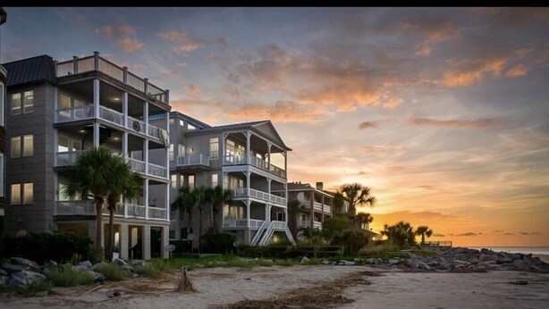 A beachfront hotel with multiple balconies and a view of the ocean at sunset. - Newly Renovated Oceanfront Condo • Right on the Beach • Beachfront • Great Views (Saint Simons Island)