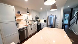 A modern kitchen with white cabinetry, stainless steel appliances, and a large marble island. - Newly Renovated Oceanfront Condo • Right on the Beach • Beachfront • Great Views (Saint Simons Island)