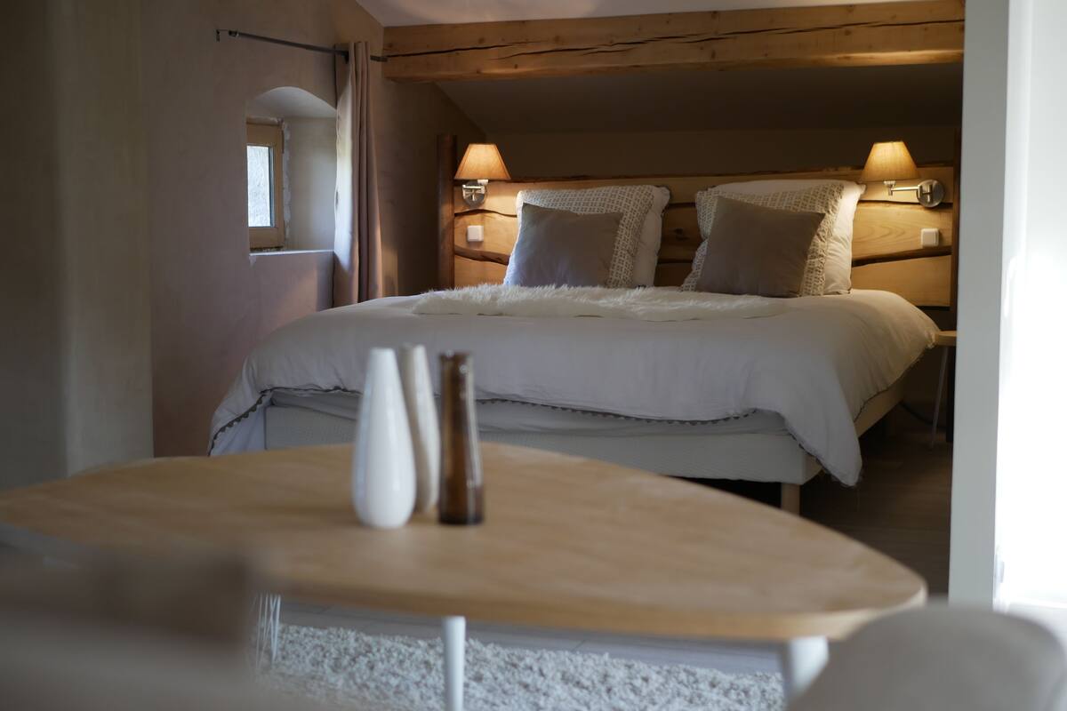 Une chambre à coucher avec un lit, des lampes de chevet, un vase et une fenêtre.