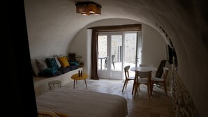 A cozy bedroom with a large bed, a small table, and a seating area with chairs. - Les Agaves (Grospierres)