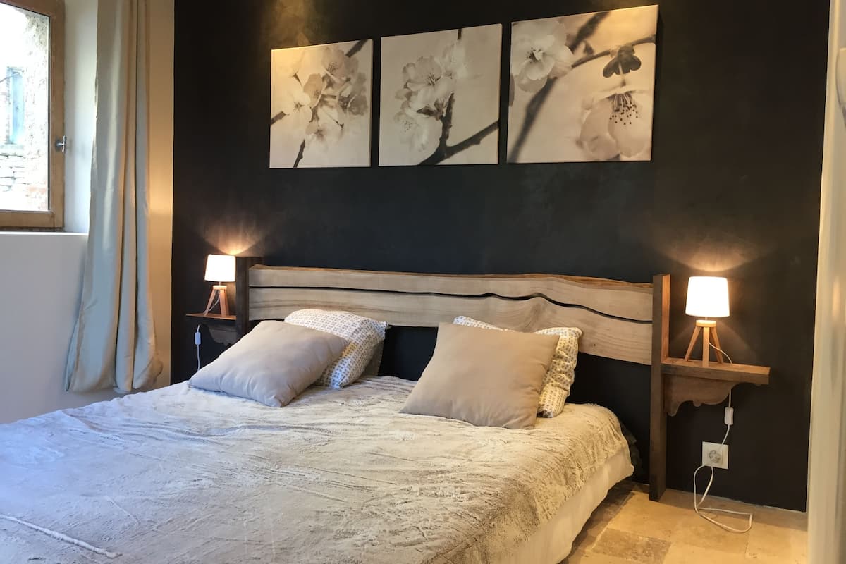 Une chambre à coucher avec un grand lit, deux lampes de chevet et trois tableaux accrochés au mur.