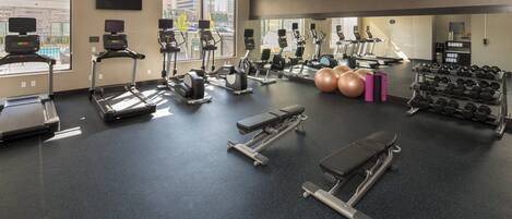 Un gimnasio con cintas de correr, elípticas, prensa de banca y mancuernas.