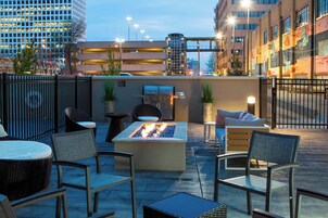 Un patio al aire libre con mobiliario, una chimenea y una parrilla.