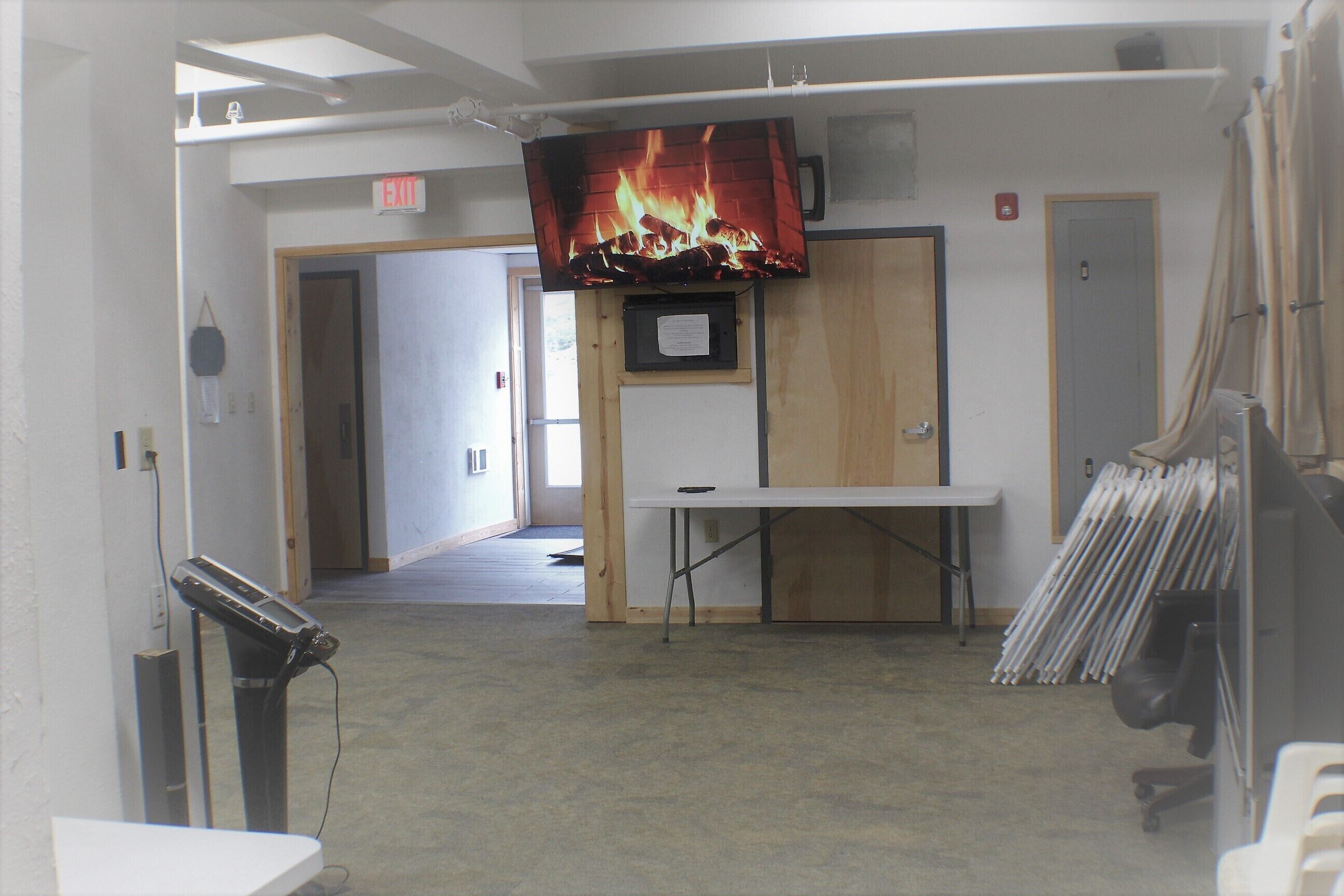 A room with a television displaying a fireplace, a table, and a door.