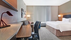 A hotel room with a bed, desk, chair, and a large window with curtains. - TownePlace Suites by Marriott Jackson Airport/Flowood (Flowood)