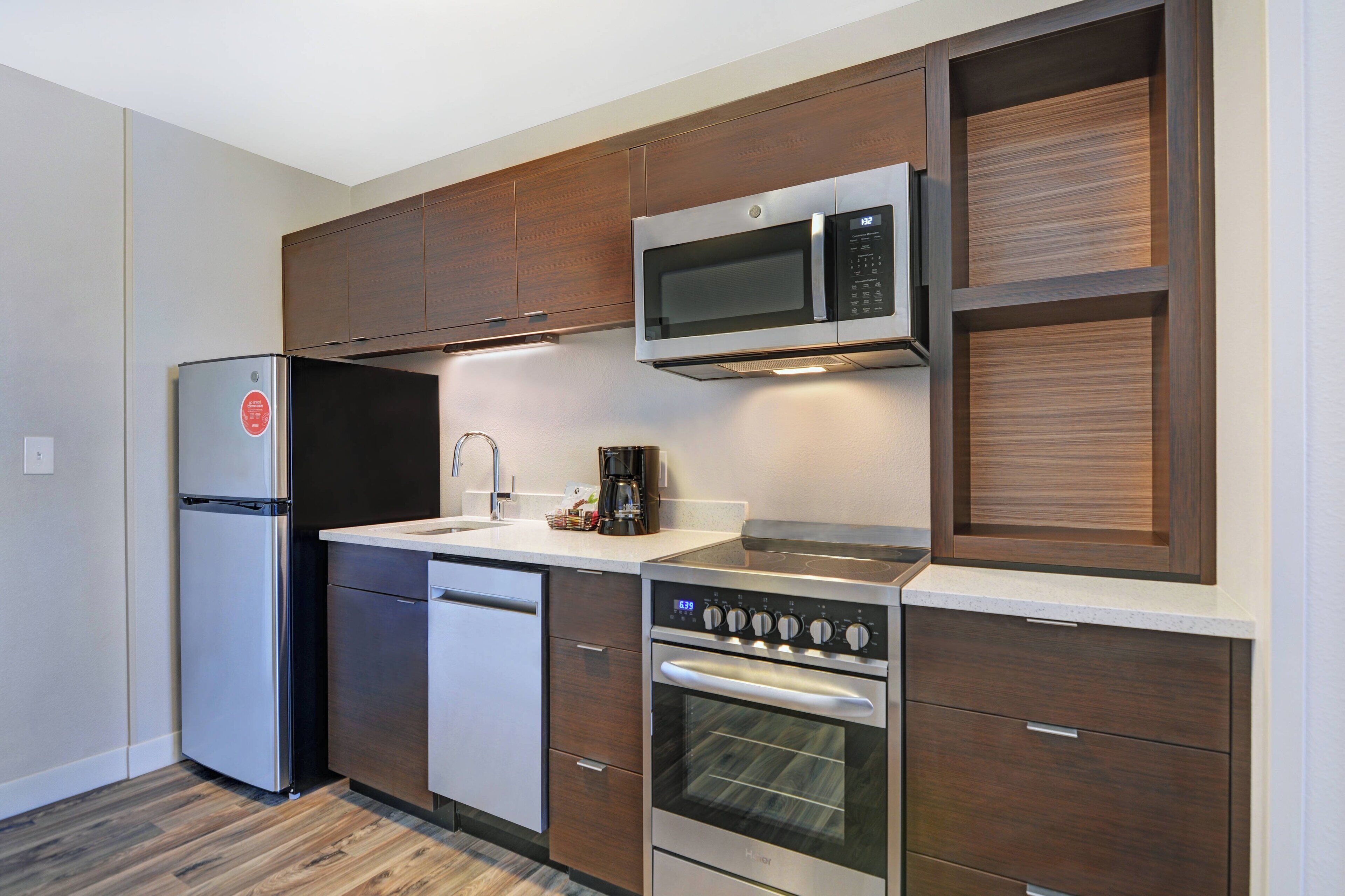 A modern kitchen with a stainless steel refrigerator, a microwave, an oven, and a dishwasher.
