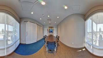 Une salle de conférence avec une grande table, des chaises et un tapis bleu.