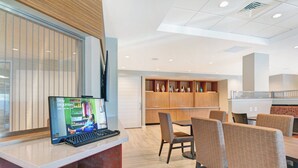 A modern hotel lobby with a reception desk, a seating area with chairs and a table, and a decorative wall with shelves. - TownePlace Suites by Marriott Jackson Airport/Flowood (Flowood)