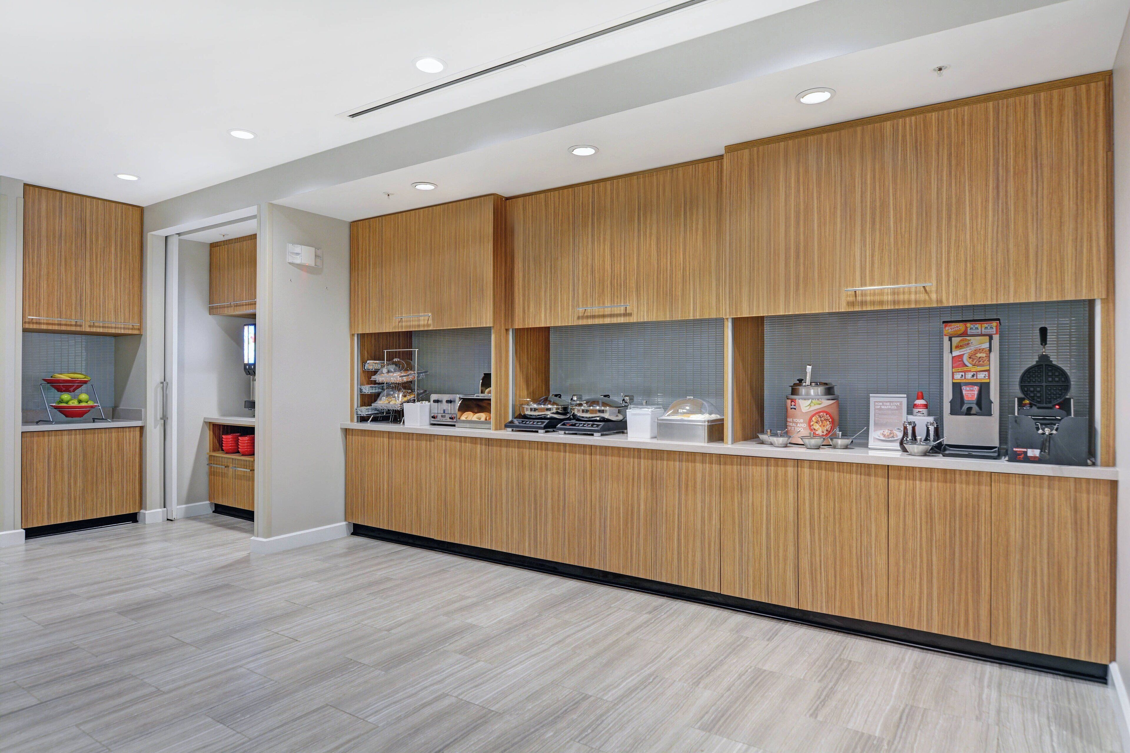 A modern kitchen with wooden cabinets, a countertop with various appliances, and a tiled backsplash.