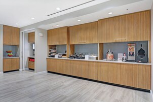 A modern kitchen with wooden cabinets, a countertop with various appliances, and a tiled backsplash.