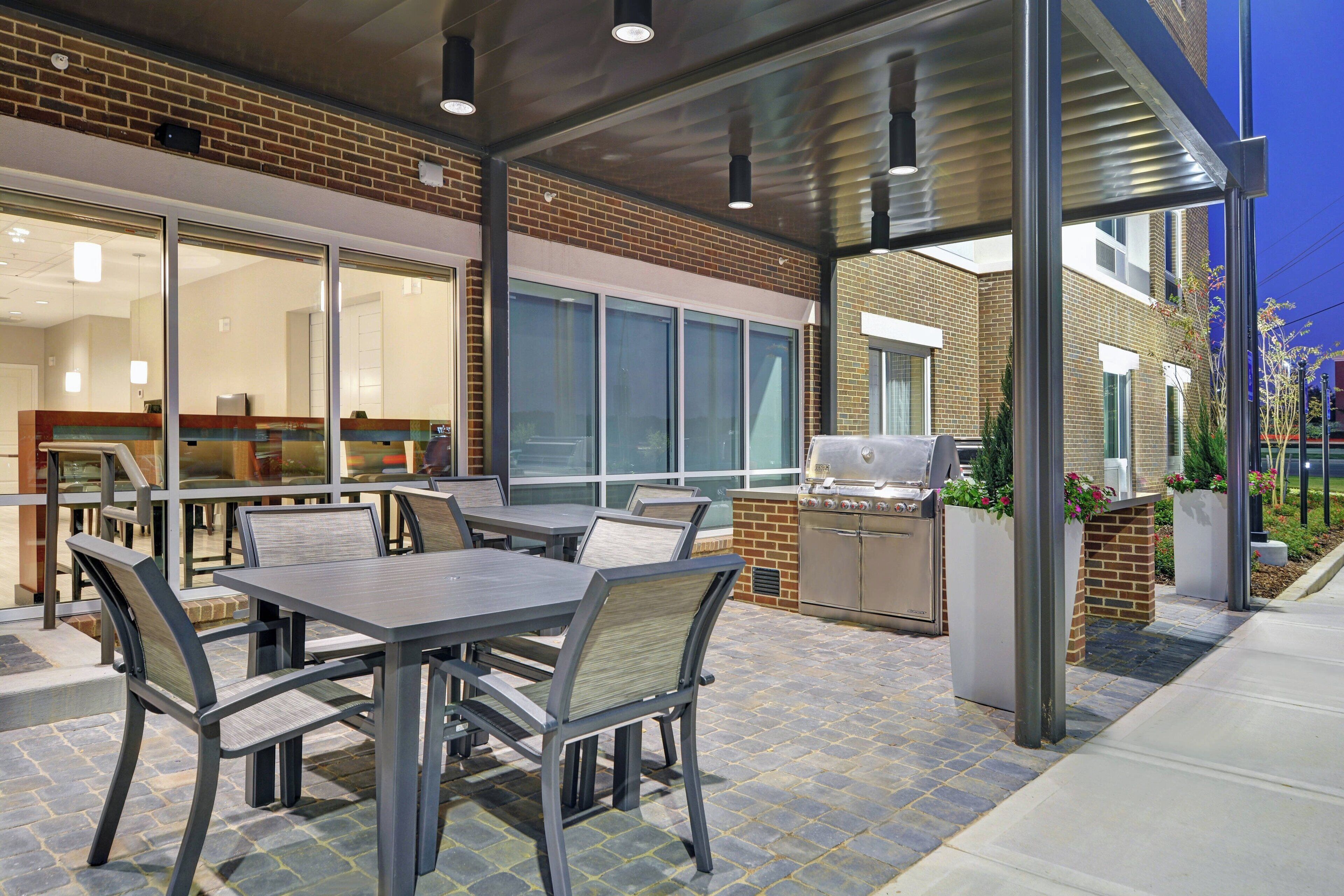 An outdoor patio area with a brick wall, large windows, and a grill station.