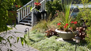 A garden with a pathway leading to a staircase, surrounded by various plants and flowers. - Perfect Kitsilano Location - 1 Bed. -1.5  Bath. (for 3 Bed. option see #430414) (Vancouver)