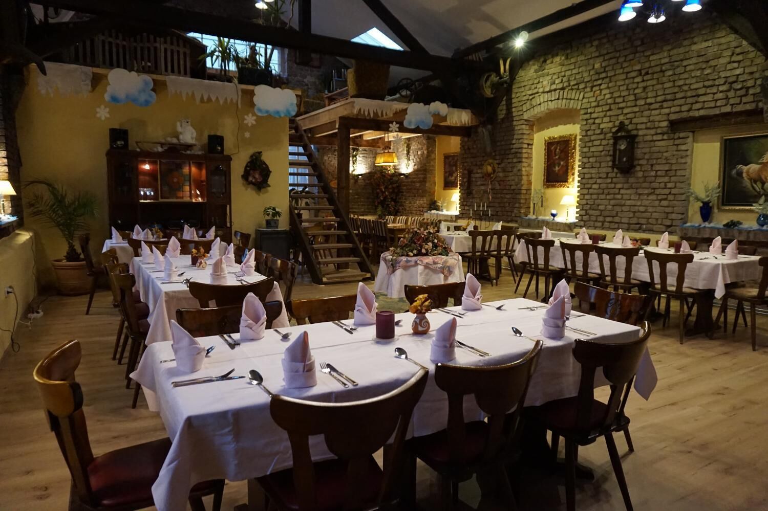 A restaurant with multiple tables set for dining, featuring a rustic interior with brick walls and wooden furniture.