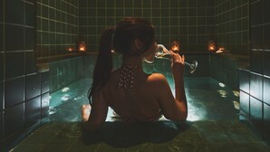 Una mujer sentada en una bañera con velas.
