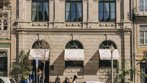 Un edificio de varios pisos con un estilo arquitectónico clásico, que presenta ventanas arqueadas y una fachada simétrica.