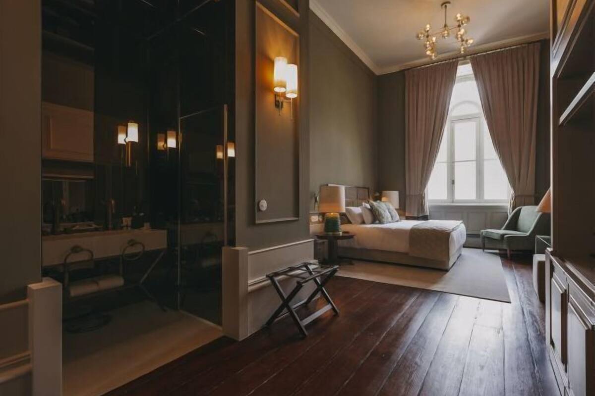 Hotellihuone, jossa on sänky, yöpöytä, lamppu ja näkymä ulos.