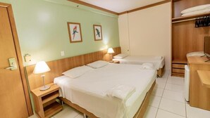 A hotel room with two beds, a wooden wardrobe, a desk, and a small shelf. - Golden Dolphin Grand Hotel - Mondial (Caldas Novas)
