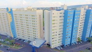 A multi-story hotel with a uniform facade, featuring a central entrance with a blue canopy. - Golden Dolphin Grand Hotel - Mondial (Caldas Novas)