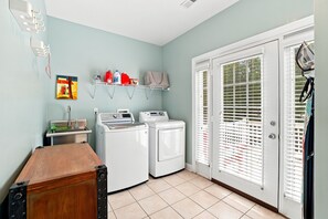 A laundry room with two washing machines, a drying rack, and a shelf with cleaning supplies. - Luxury Lake House, Pool, Hot tub, Dock, Beach, Game room, Boat Rental available (Charlotte)