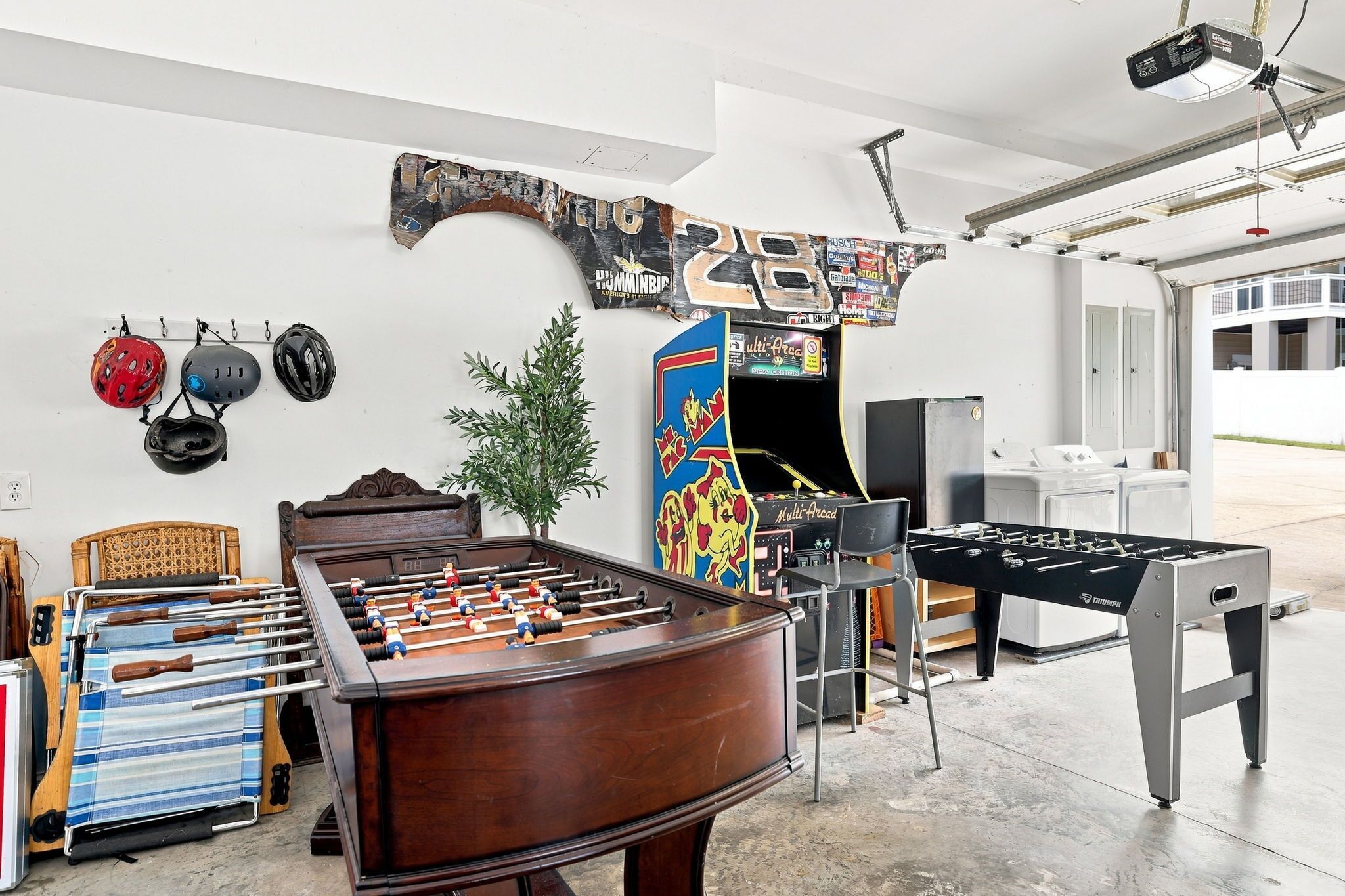 A room with a foosball table, a ping pong table, and a wall-mounted foosball table.