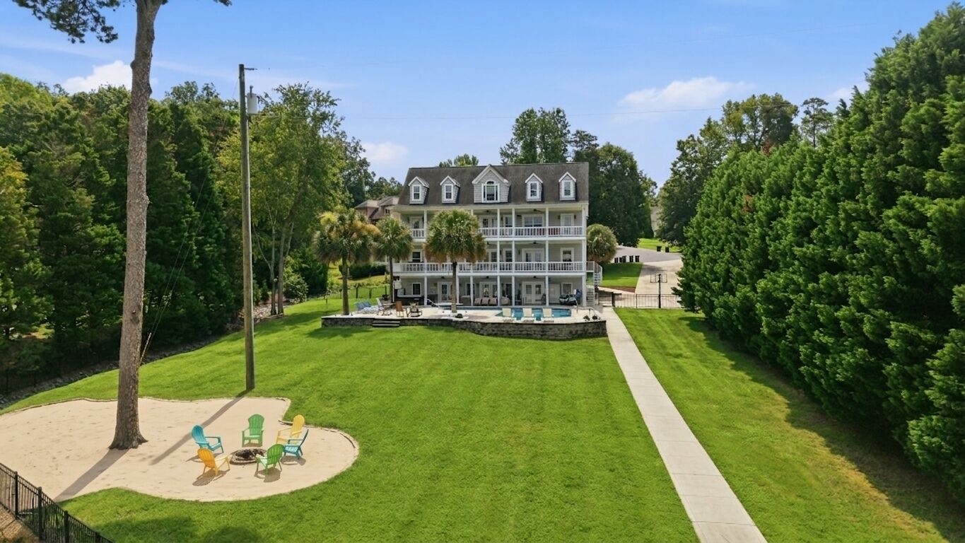 A large two-story house with a front porch, a swimming pool, and a well-maintained lawn.