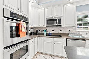 A modern kitchen with stainless steel appliances, white cabinetry, and a tiled backsplash. - Luxury Lake House, Pool, Hot tub, Dock, Beach, Game room, Boat Rental available (Charlotte)