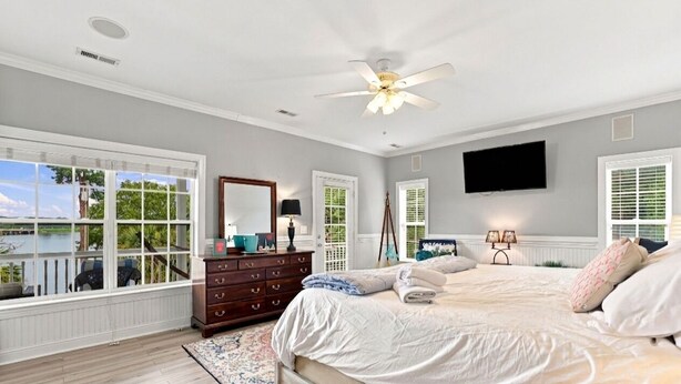 A bedroom with a large bed, a dresser, a ceiling fan, and a TV mounted on the wall. - Luxury Lake House, Pool, Hot tub, Dock, Beach, Game room, Boat Rental available (Charlotte)