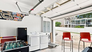 A garage with a washing machine, a foosball table, and two red chairs. - Luxury Lake House, Pool, Hot tub, Dock, Beach, Game room, Boat Rental available (Charlotte)