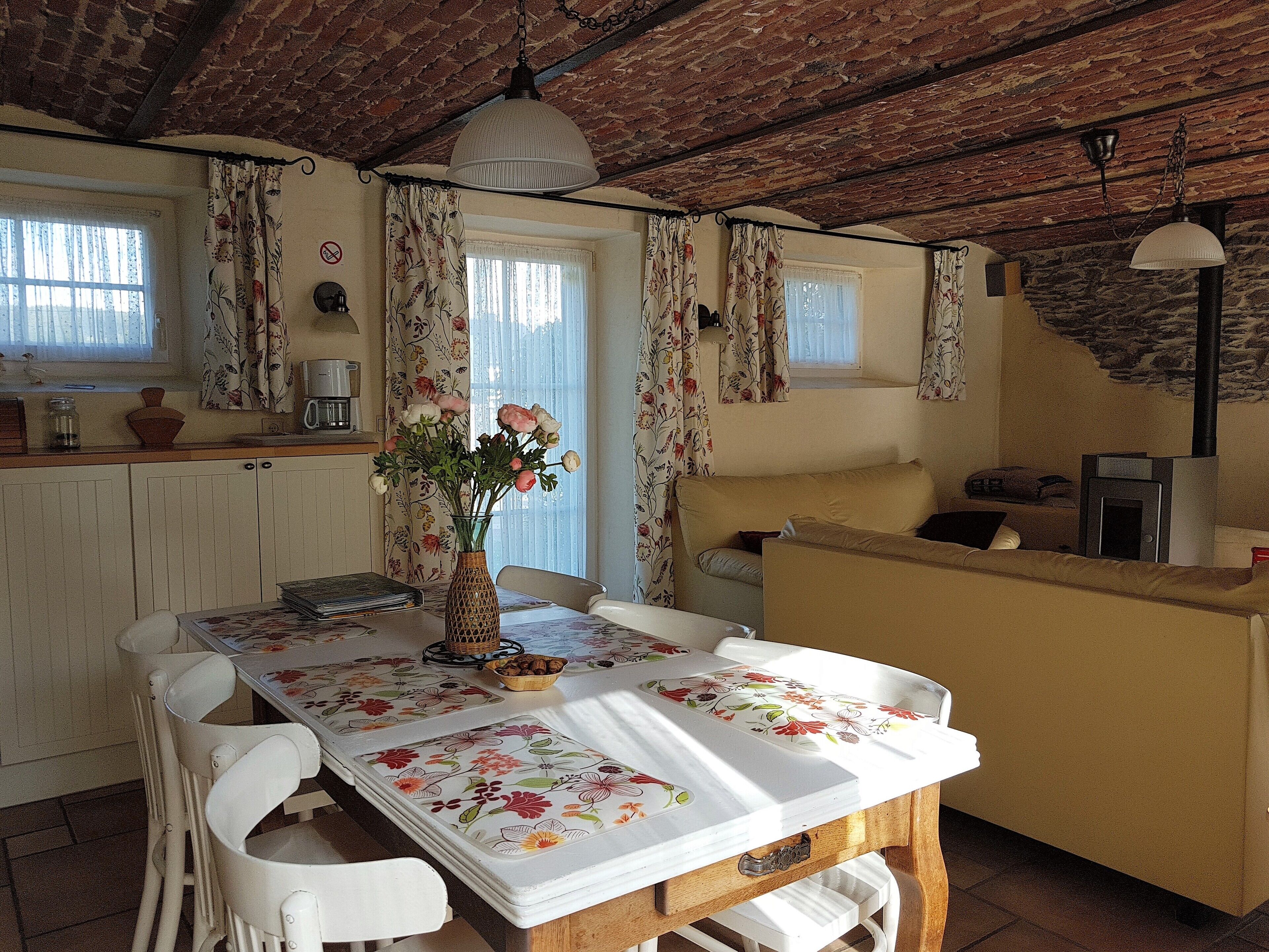 Una cocina acogedora con una mesa de comedor, sillas y un florero con flores.