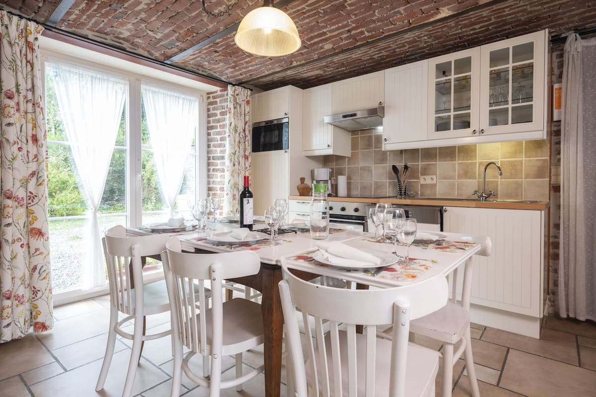 Un coin repas avec un plafond en briques, des meubles blancs et une table dressée pour quatre personnes.