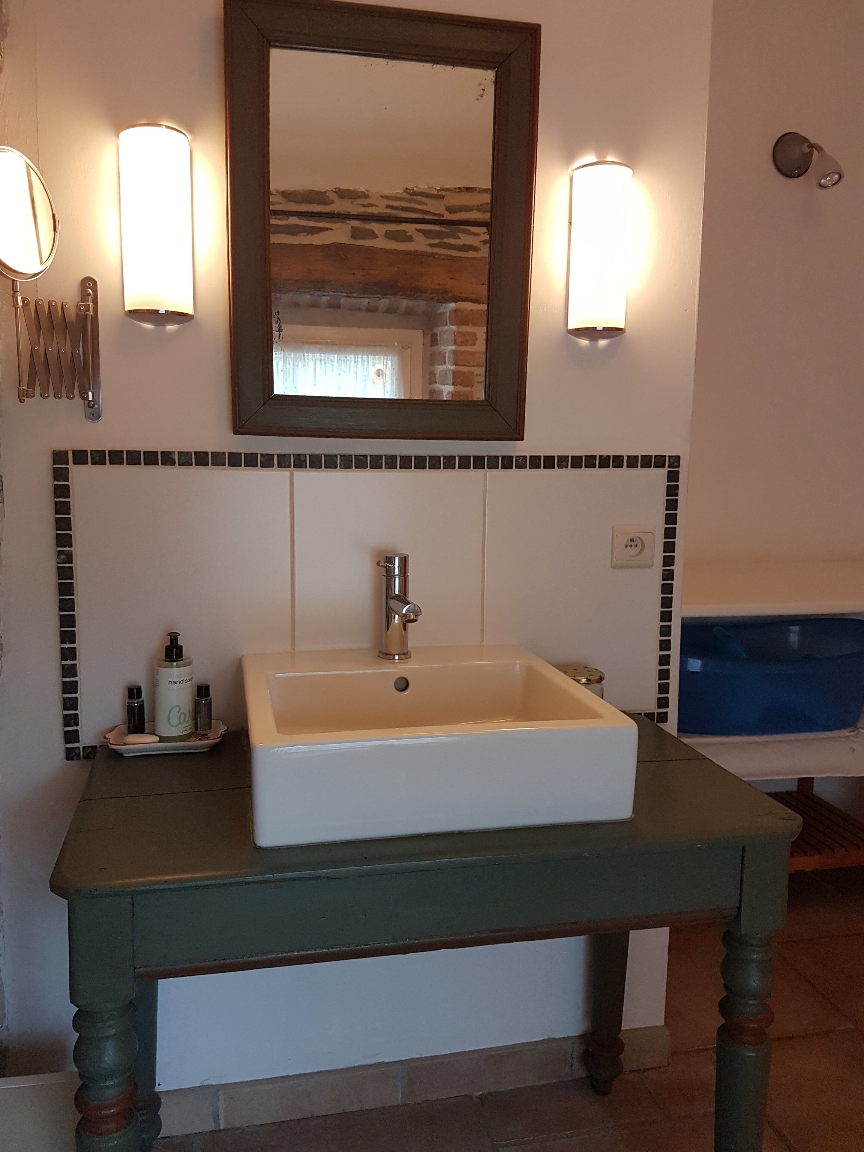 Un bagno con un lavandino bianco, uno specchio e due luci a parete.