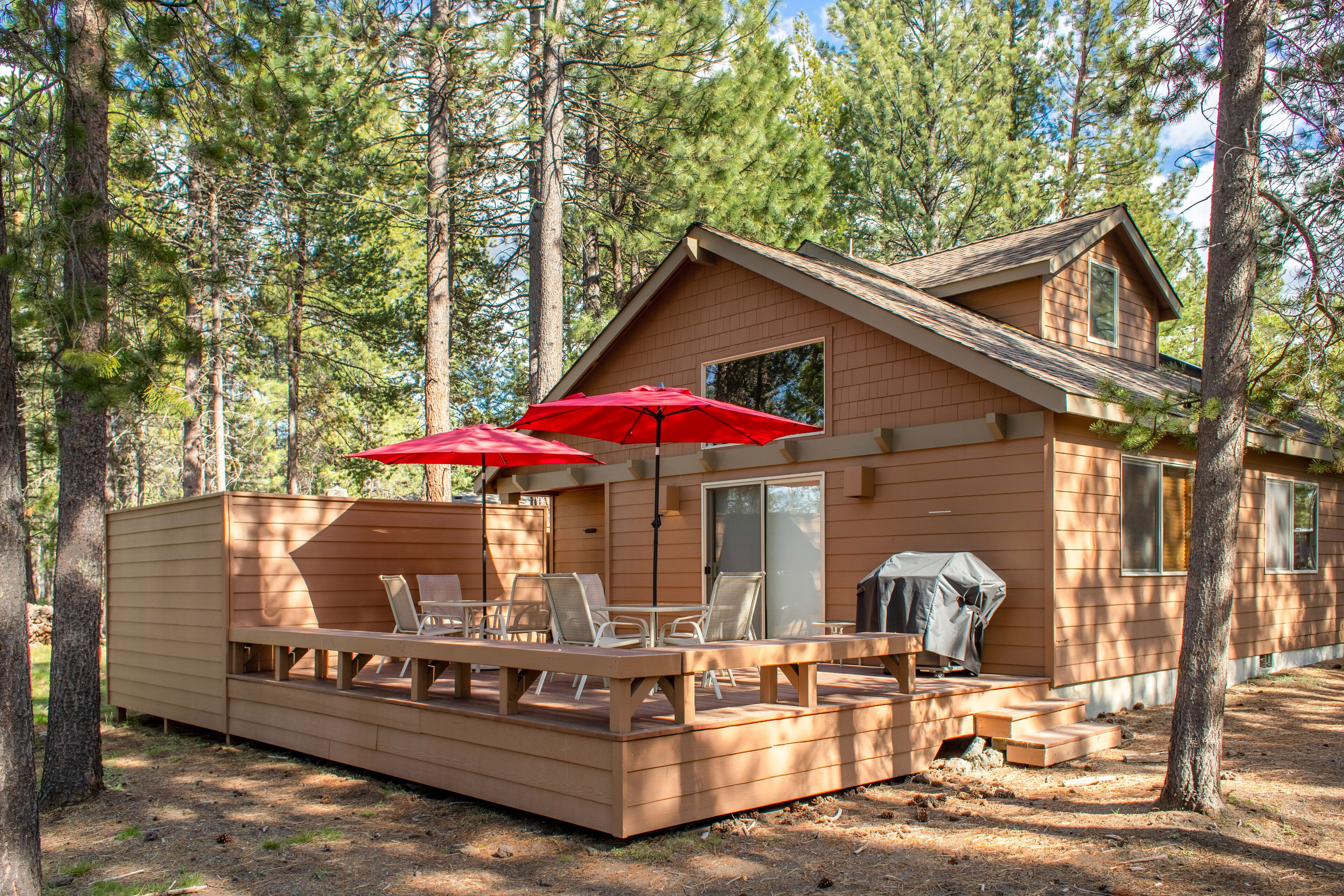A cabin with a deck, outdoor seating, and a barbecue area.