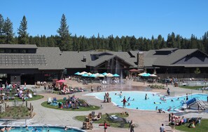 A resort with multiple swimming pools, lounge areas, and a large building with a stone facade.