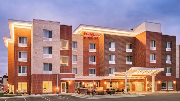 Ein mehrstöckiges Hotel mit einem gut sichtbaren 'TownePlace by Marriott'-Schild, einem Außenbereich mit Sitzgelegenheiten und einem überdachten Eingang.