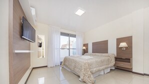 A modern hotel room with a large bed, a flat-screen TV mounted on the wall, a window with curtains, and a bedside table with a lamp. - X52 Independencia Apartment (Córdoba)