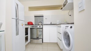 A compact kitchen with a refrigerator, oven, microwave, and washing machine. - X52 Independencia Apartment (Córdoba)