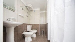 A modern bathroom with a white sink, two toilets, and a glass shower enclosure. - X52 Independencia Apartment (Córdoba)