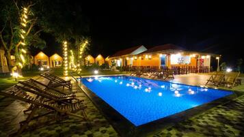 Una piscina al aire libre, sombrillas, sillones reclinables de piscina