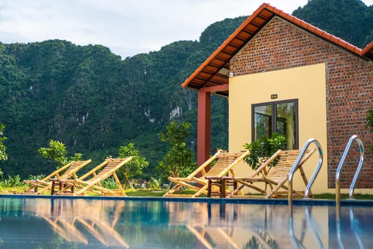 A poolside area with wooden lounge chairs and a small brick building with a window.