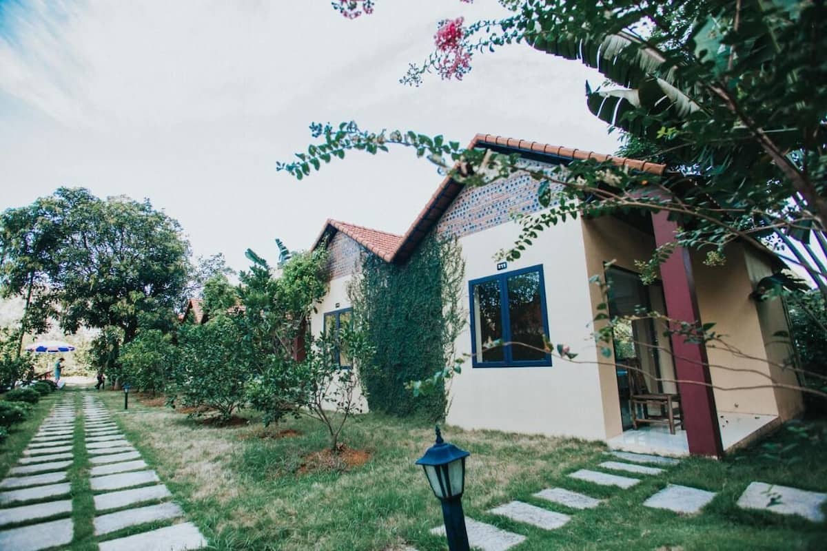 A garden pathway leading to a house with a tiled roof and a small porch.