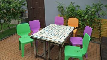 A small outdoor seating area with a wooden table and colorful plastic chairs.