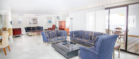 Un salón espacioso con un amplio sofá, una mesa de centro y una zona de comedor con mesa y sillas.