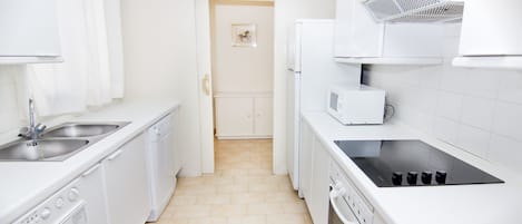 A modern kitchen with white appliances, a dishwasher, a stove, and a microwave.