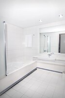 Ein modernes Badezimmer mit einer gläsernen Duschkabine, einer großzügigen Badewanne und einem Doppelwaschtisch.