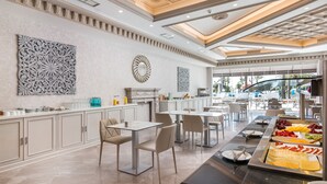 Comedor moderno de hotel con servicio de buffet, armarios blancos y decoración contemporánea.