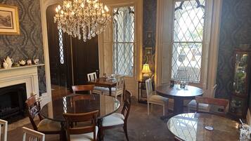 Uma sala de jantar com candelabro, lareira e janelas amplas com vista.