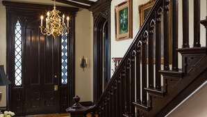 Una imponente escalera con barandillas de madera oscura y un candelabro.