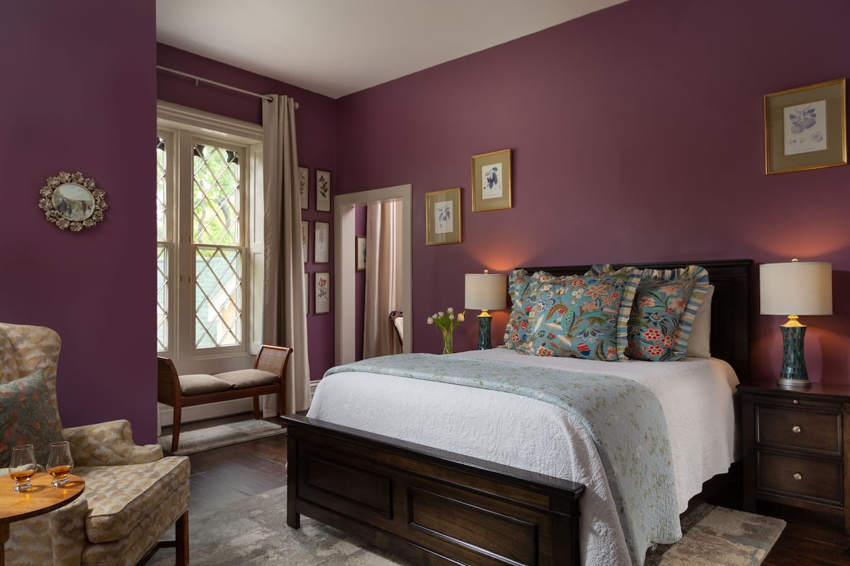 Une chambre à coucher avec un lit, des tables de chevet, une chaise et une fenêtre avec des rideaux.